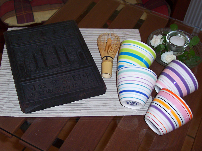 Chinesischer Teeziegel, japanischer Teebesen und Teeschalen.